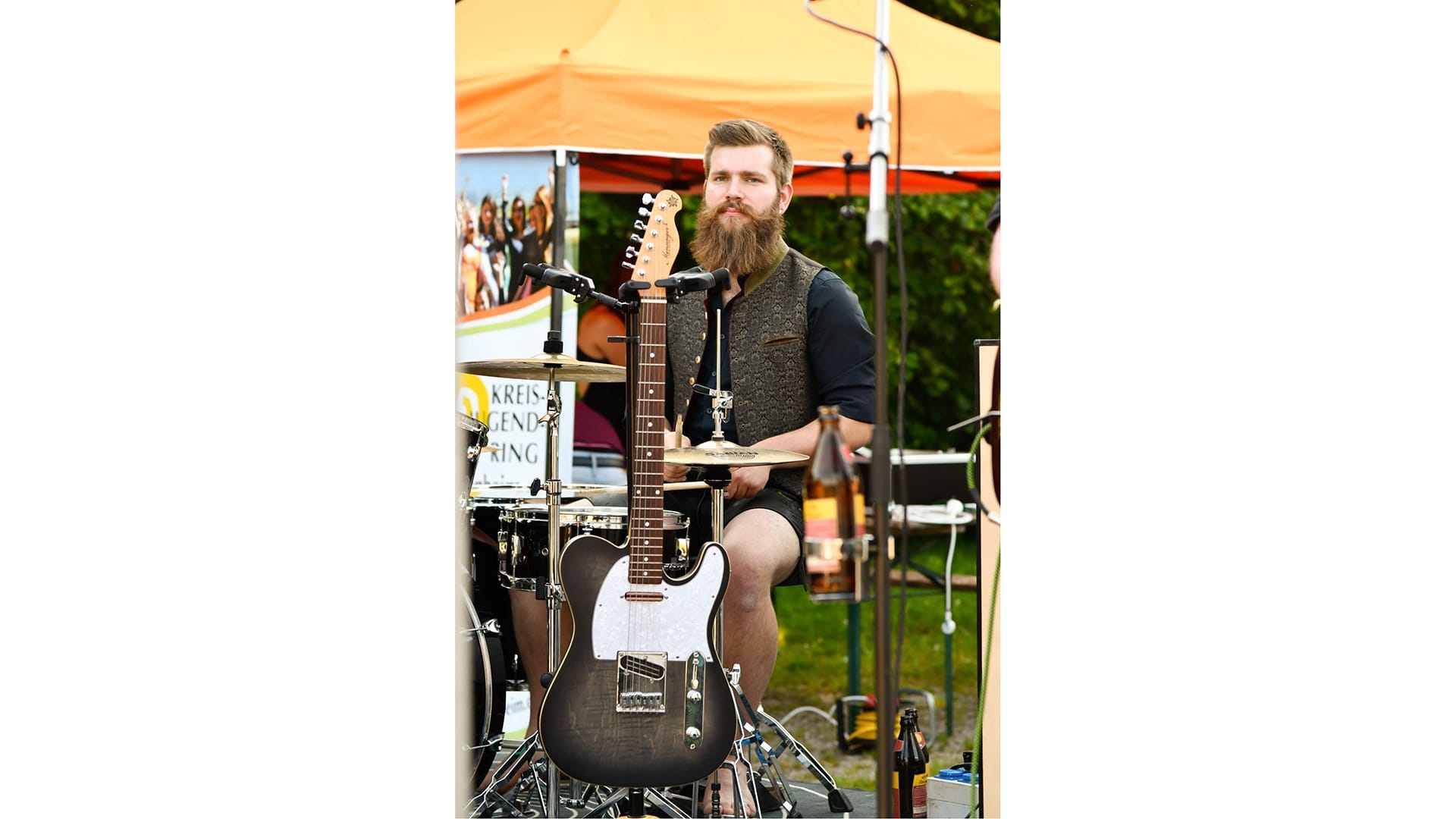 Ein junger Mann mit Vollbart mit Drumsticks am Schlagzeug