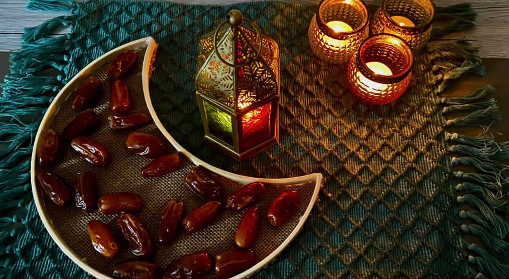 Foto: Ein halbmondförmiger Teller mit Datteln und Kerzen auf einer blauen Tischdecke