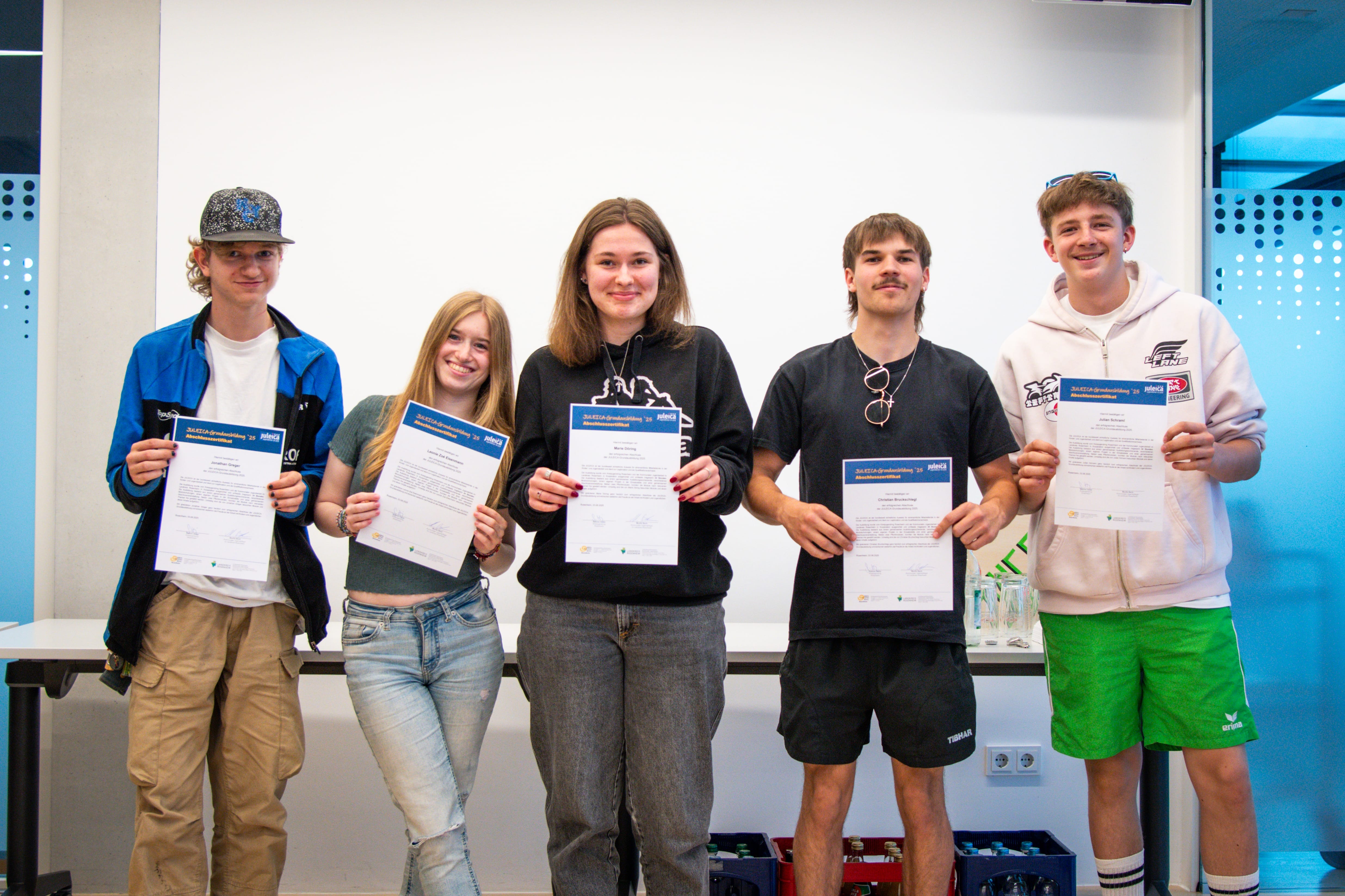 Foto: Fünf Jugendliche mit JULEICA Zertifikat in den Händen lachen in die Kamera