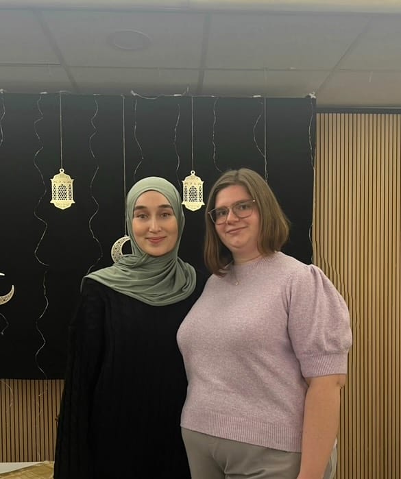 Foto: Zwei junge Frauen, eine davon mit Kopftuch, die andere ohne