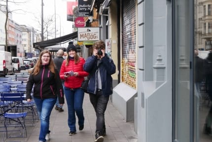 Drei junge Leute mit Kamera und Notizblock unterwegs in den Straßen von Köln