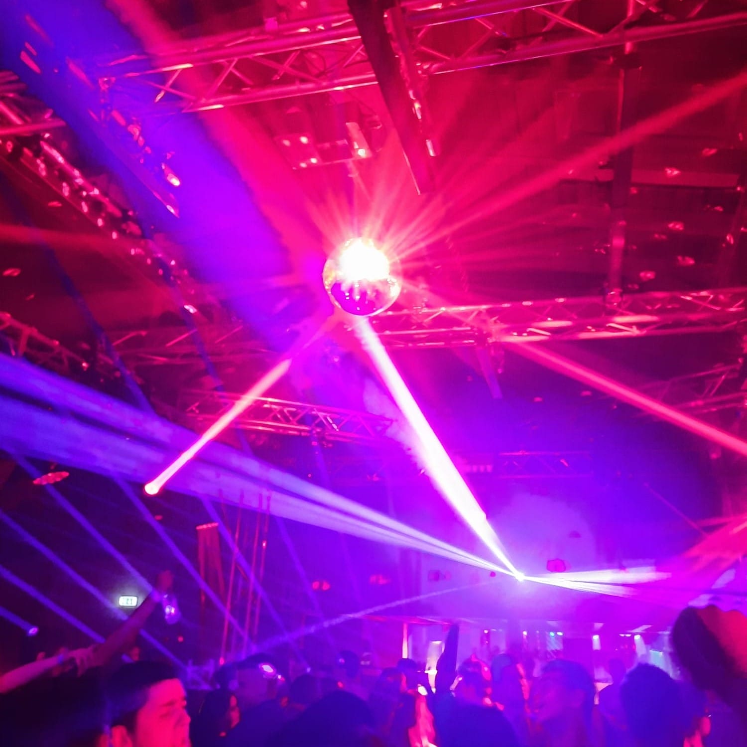 Foto: Bunte Partylichter strahlen von der Decke runter auf eine gut besuchte Tanzfläche