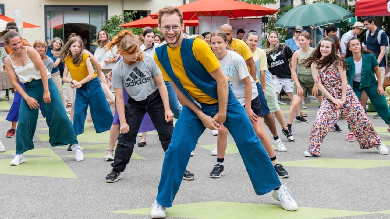 Foto: Eine Gruppe junger Menschen in modischer kleidung tanzt auf einem städtischen Platz eine Hip Hop Chroreographie
