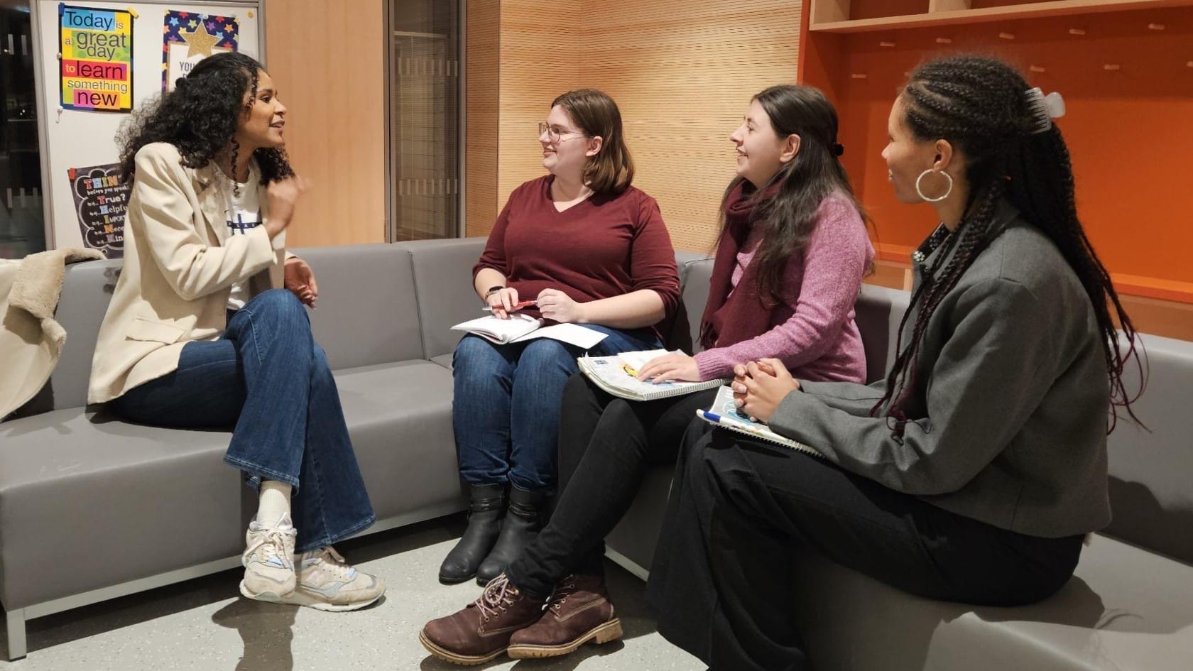 Foto: Vier junge Frauen sitzen auf einem Ecksofa und reden angeregt miteinander