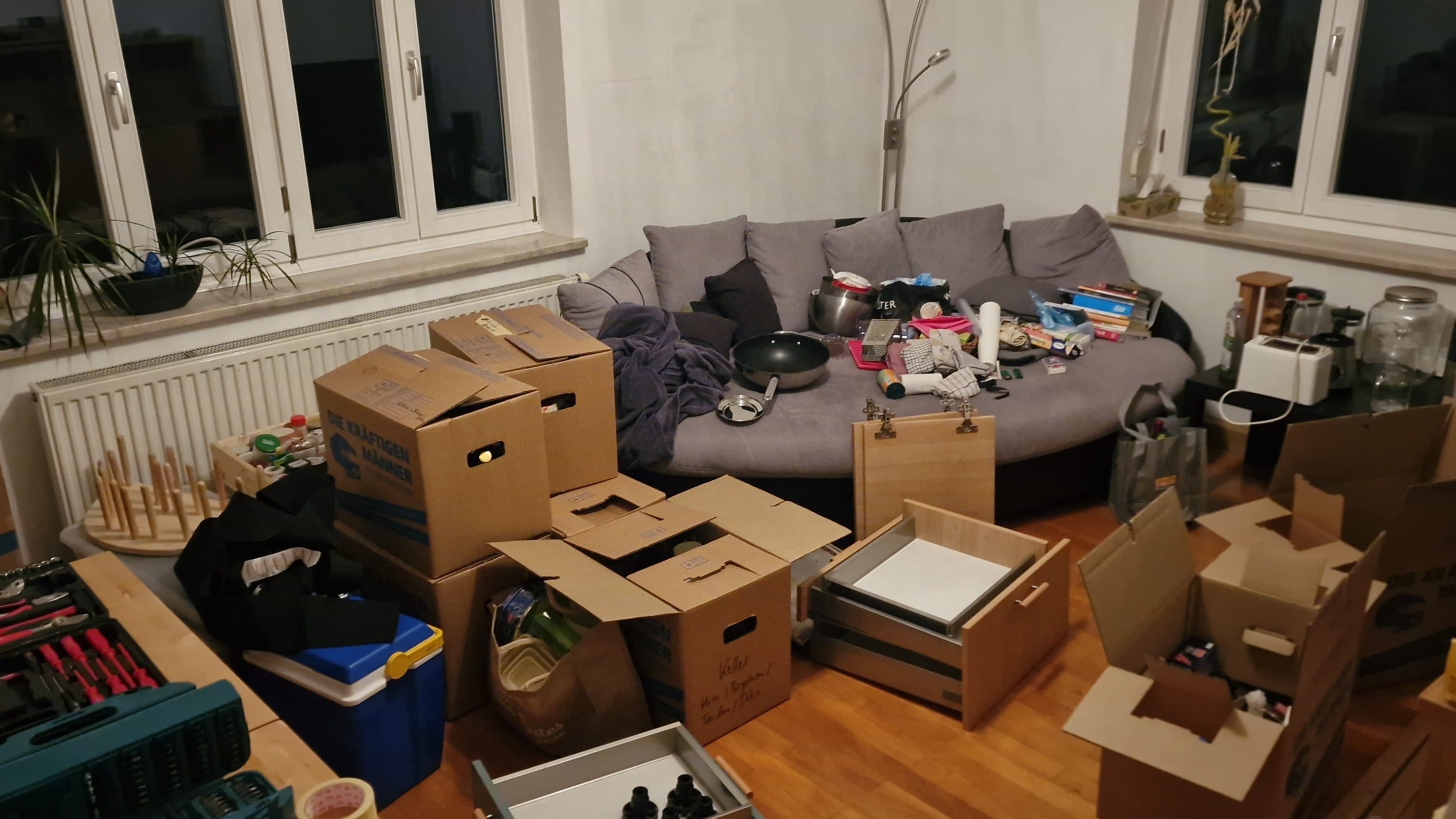 Foto von einem chaotischen Wohnzimmer mit diversen Kisten, Schubladen und Kartons verteilt
