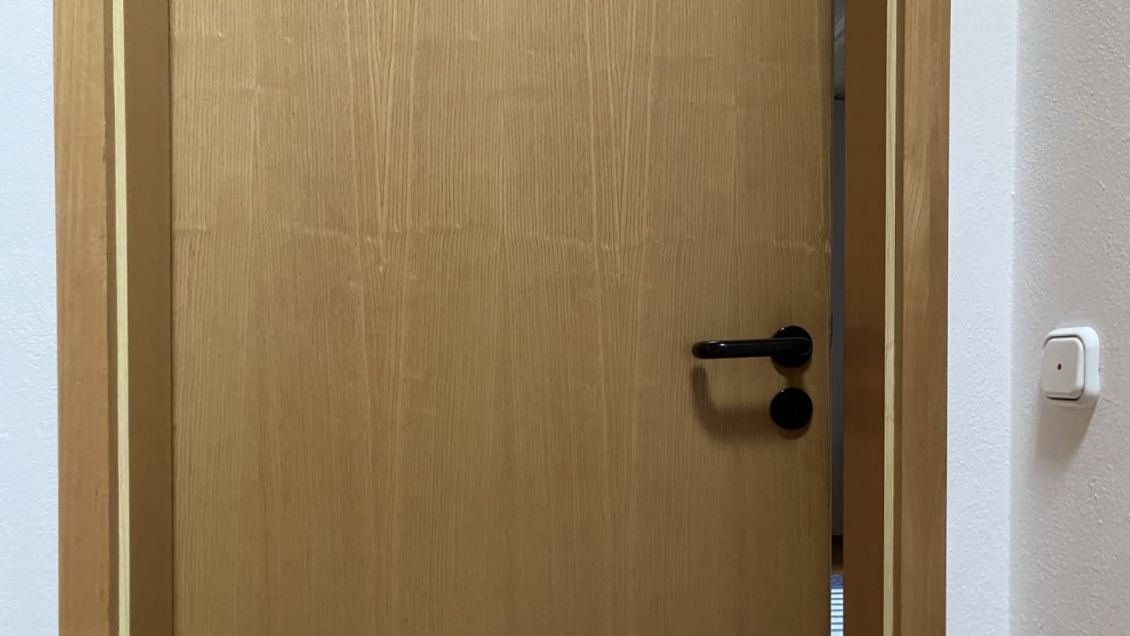 Foto: Eine Zimmertür, die nur einen sehr kleinen Spalt weit offen steht, so dass man kaum hineinsehen kann