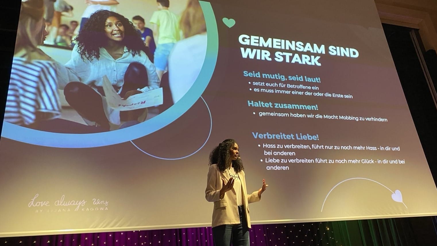 Foto: Lijana auf der Bühne, auf der Leinwand hinter ihr die Botschaft