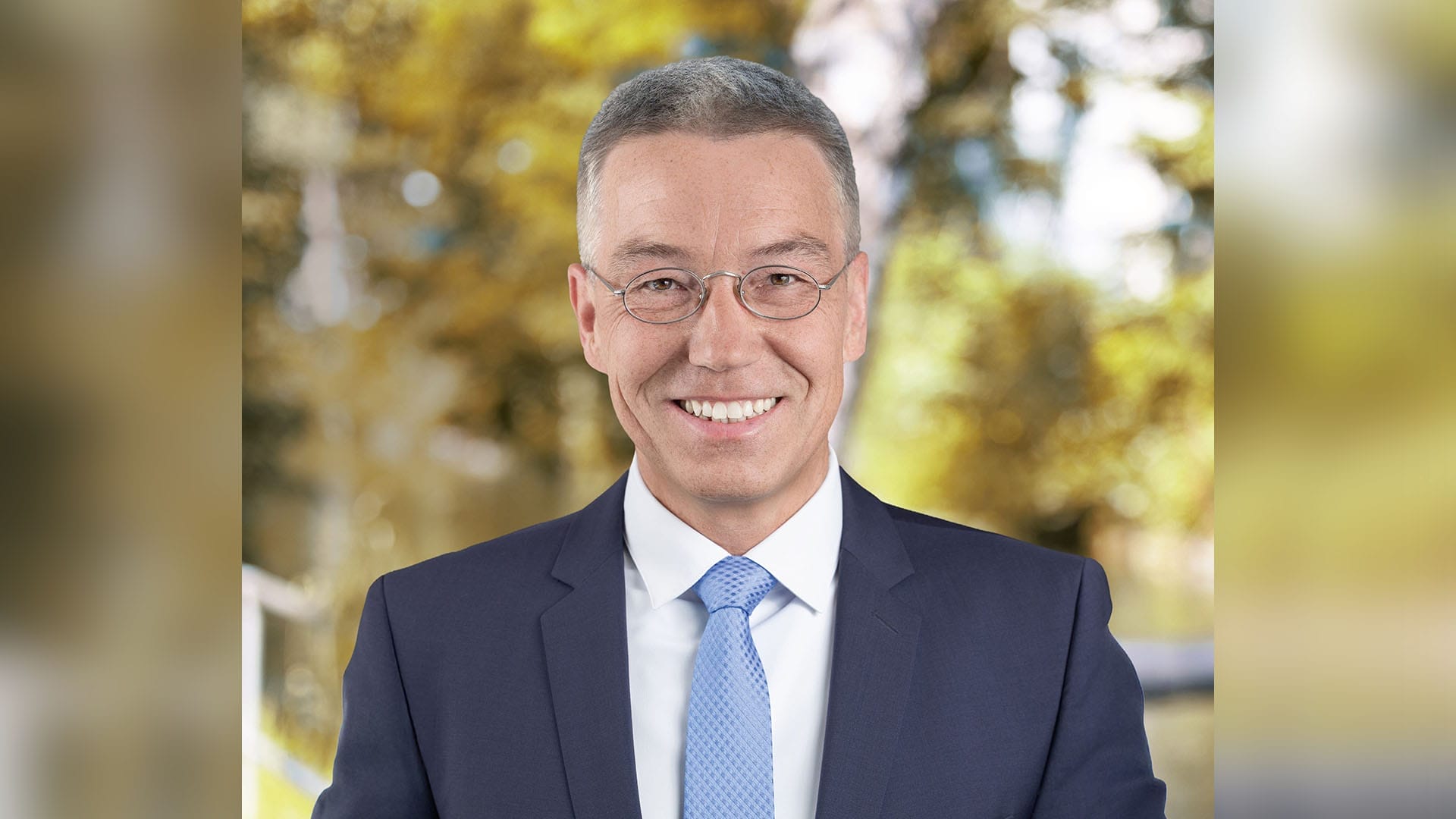 Portrait von Otto Lederer mit unscharfen Laubbäumen im Hintergrund