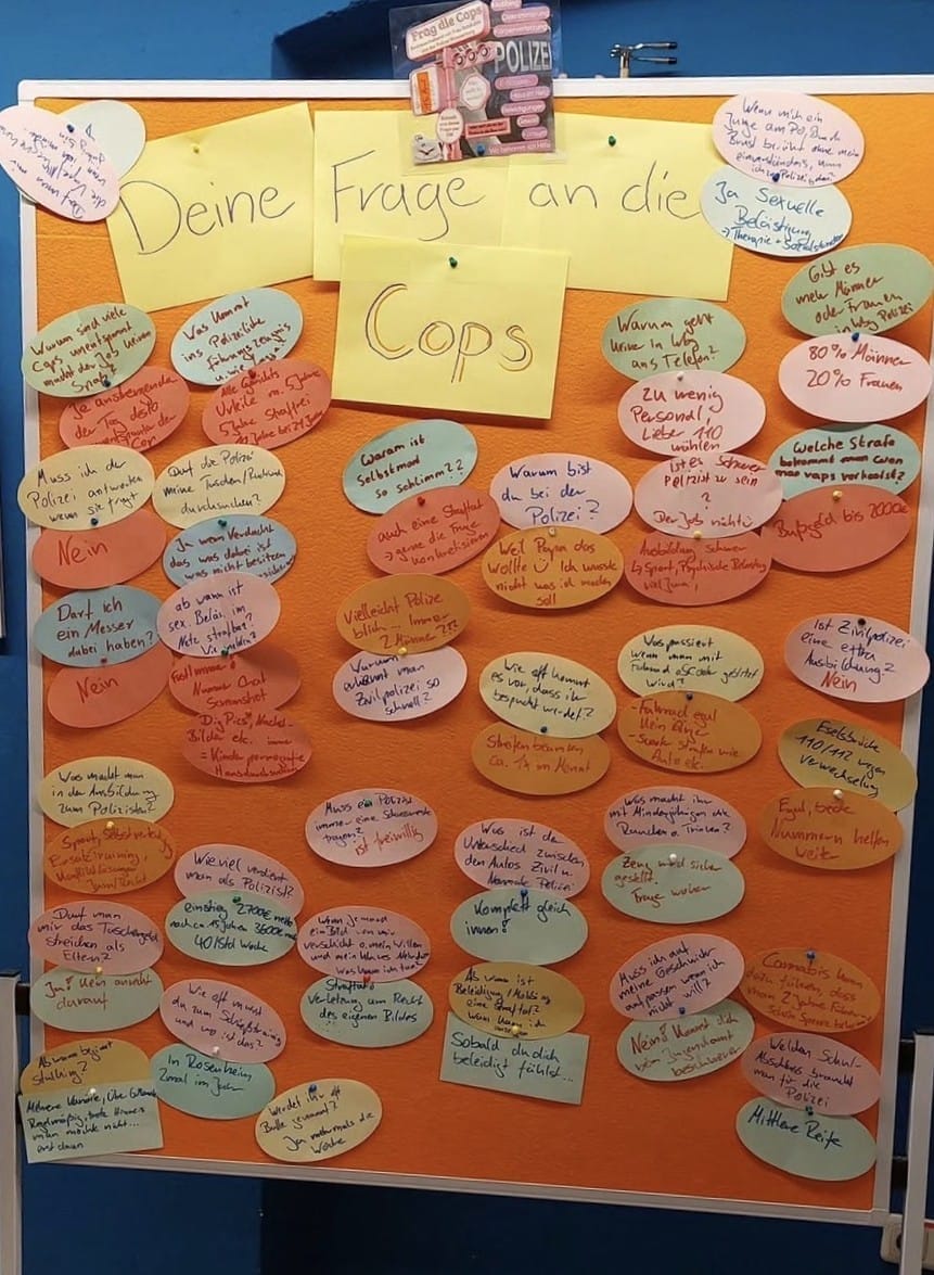 Foto: Auf einer Pinnwand heften auf bunte Zettel geschriebene Fragen von Jugendlichen und Antworten von einer Polizistin.