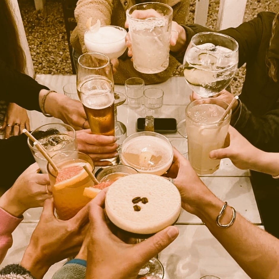 Foto: Viele verschiedene Drinks in Gläsern, mit denen sich mehrere Leute zuprosten