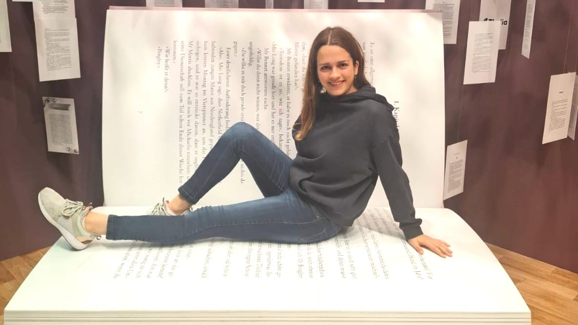 Foto von Ronja, wie sie in einem überdimensional großen aufgeschlagenen Buch posiert
