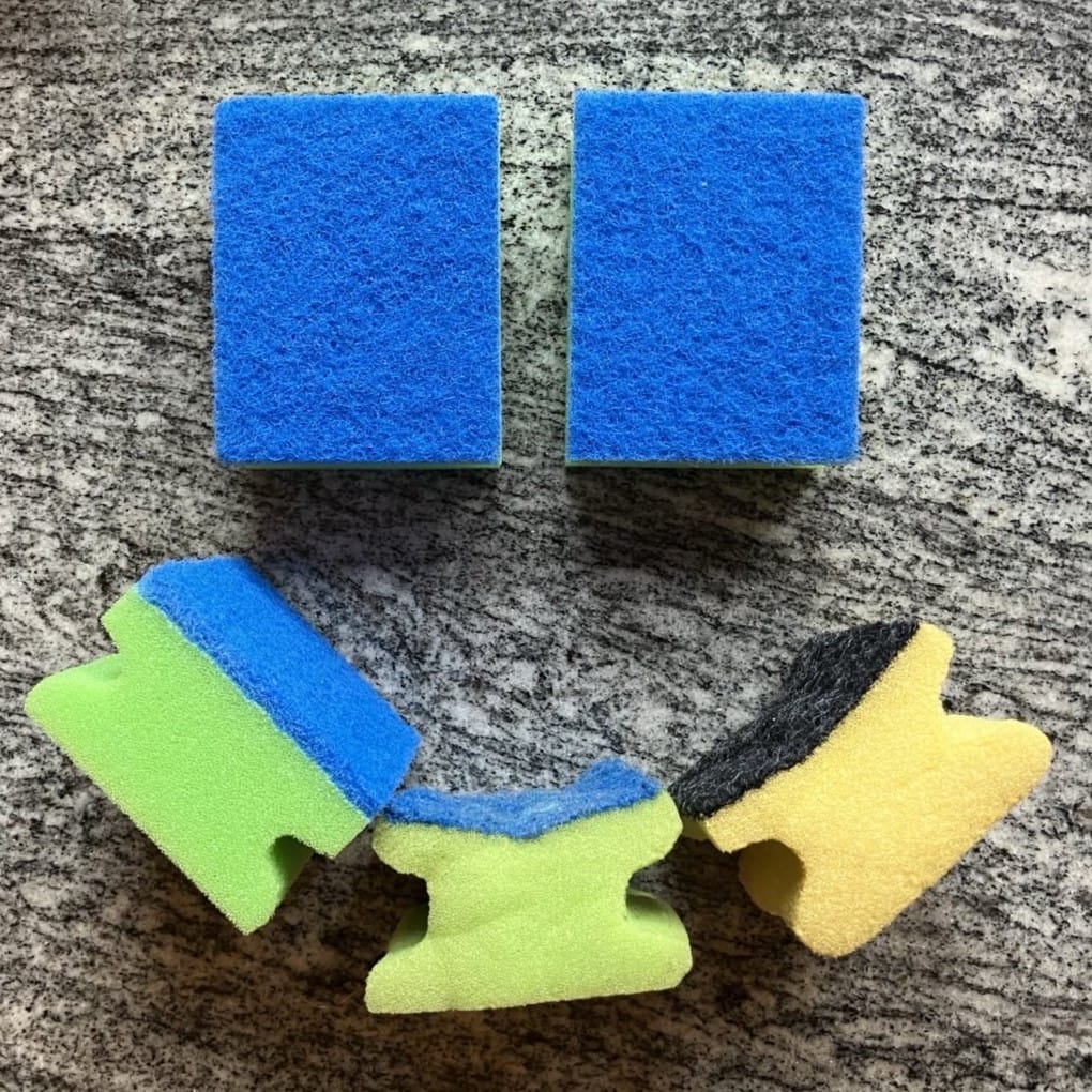 Foto: Vier grüne und ein gelber Spülschwamm bilden ein Smiley-Gesicht