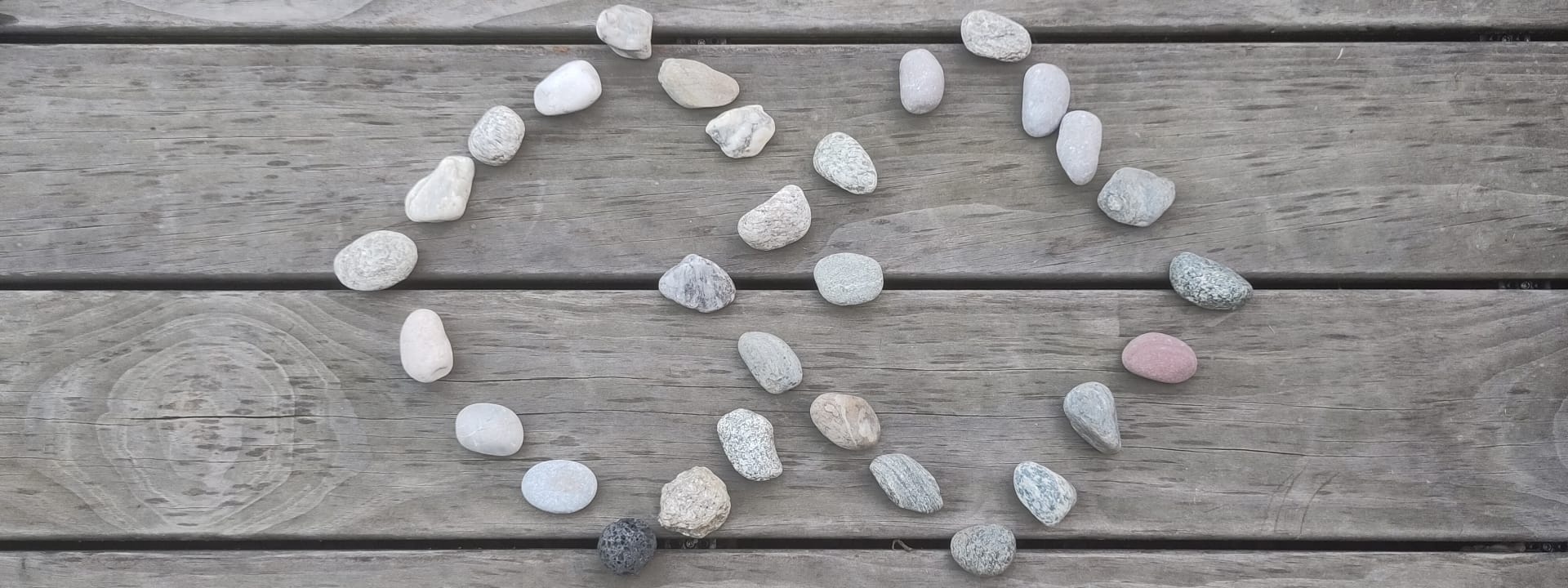 Foto: Hier sieht man zwei aus Steinen gelegte rautenartige Quadrate, die sich in der Mitte überschneiden auf einem Holzboden.