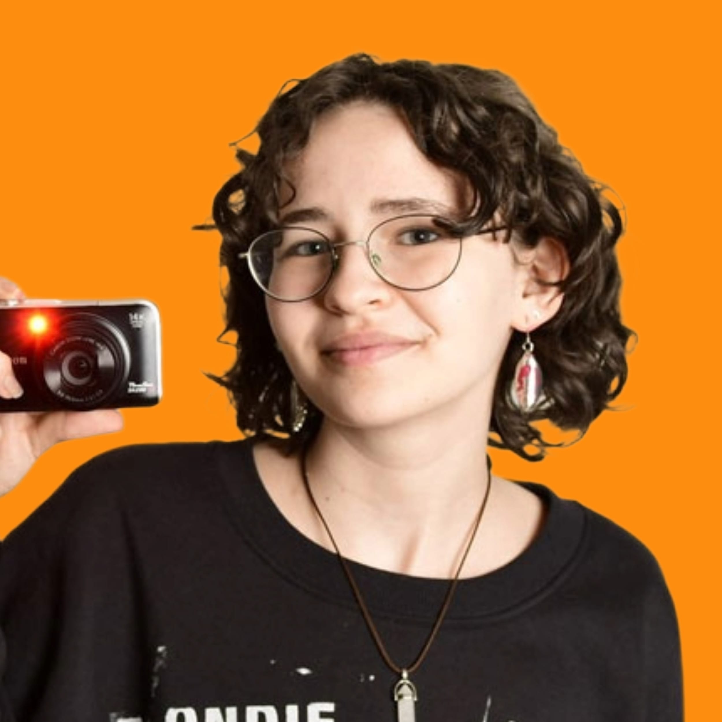 Portrait-Foto einer junge Frau mit Locken, einer Brille und einer Mini-Kamera in der Hand