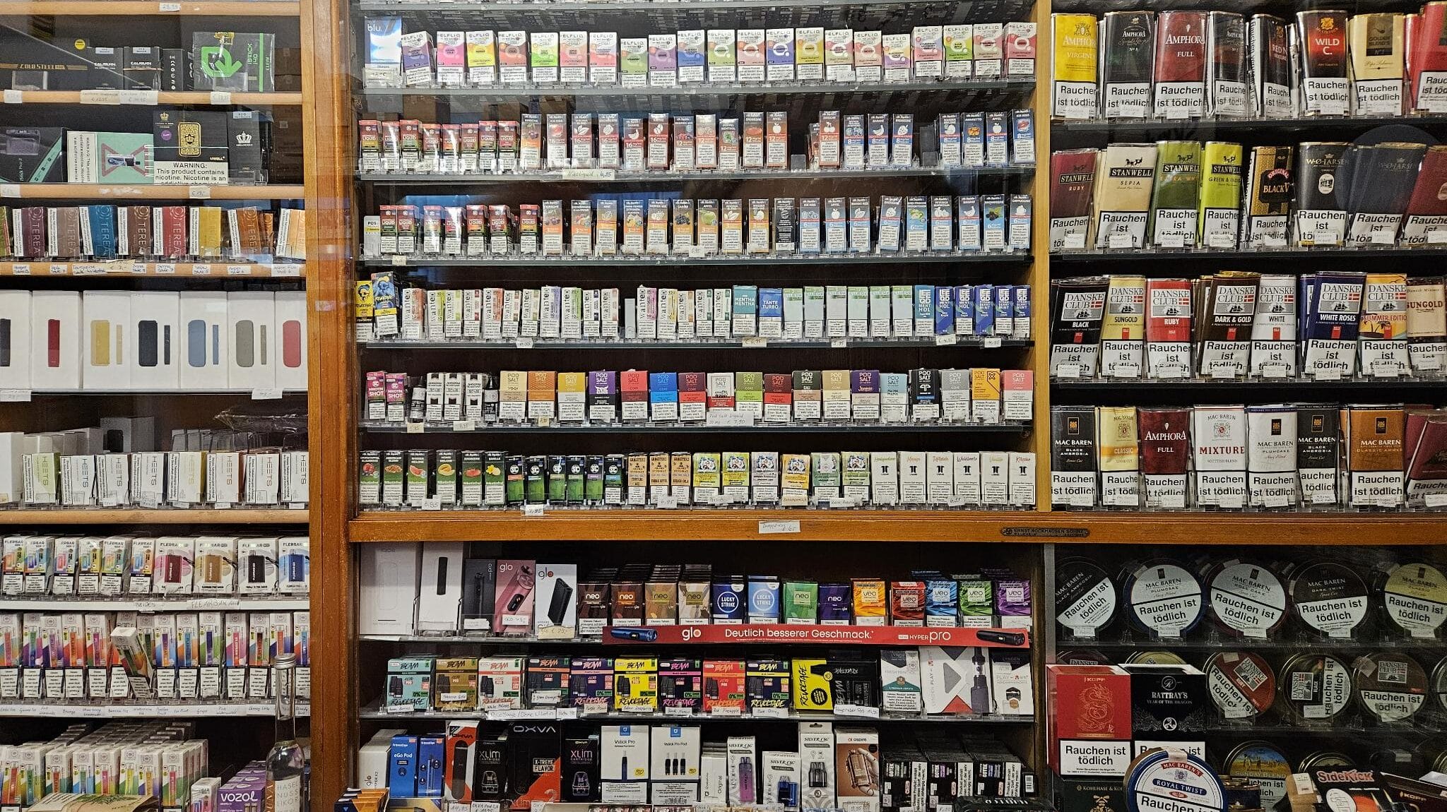 Foto: Ein Regal aus einem Shop für Rauchwaren, voll mit Tabakbeuteln, E-Zigarretten und Vapes